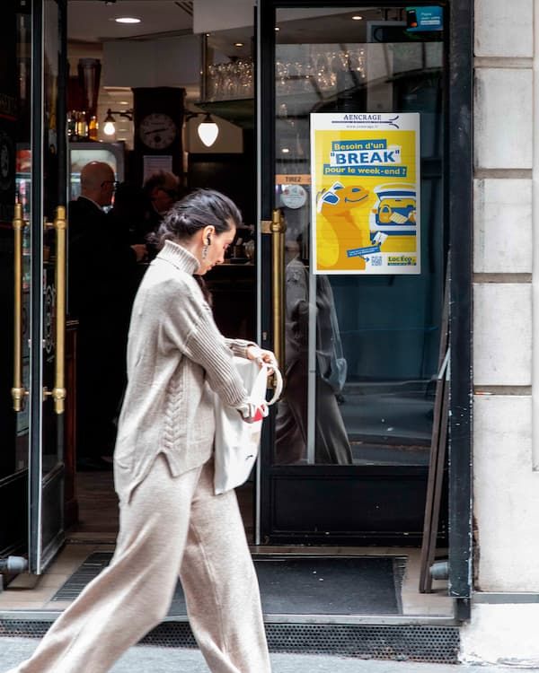 Affiche publicitaire sur la vitrine d'un commerçant avec une passante