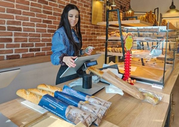 Une boulangère présente des baguettes avec leurs sachets publicitaires
